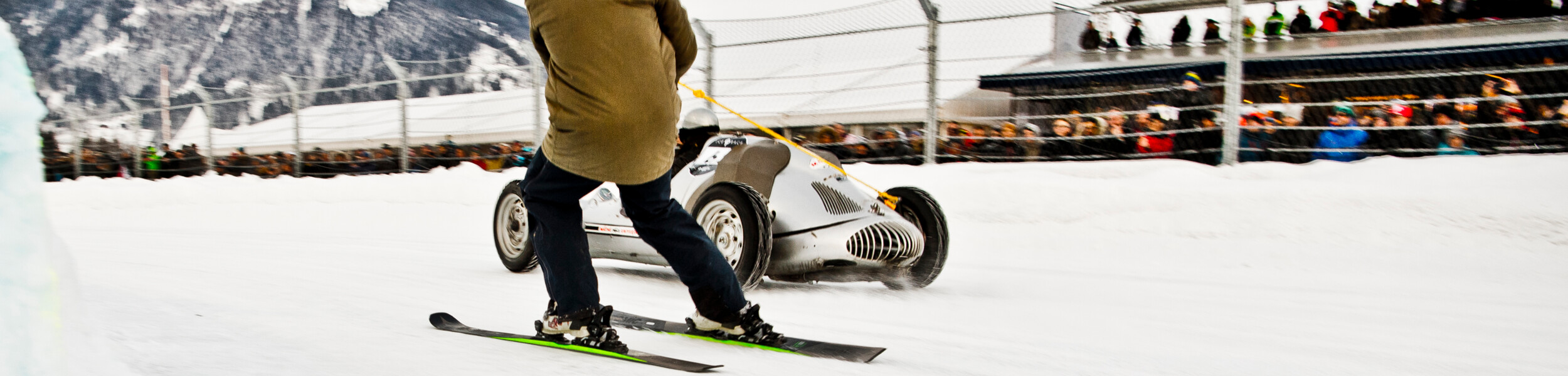 Skifahrer wird von Oldtimer-Rennauto gezogen