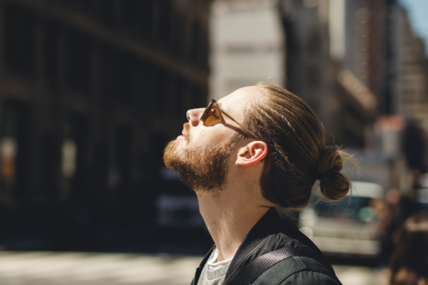 Ein junger Mann streckt sein Gesicht in die Sonne